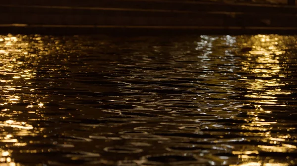 Hermosa vista nocturna de un estanque de la ciudad con ondas. Imágenes de archivo. Primer plano de la superficie del agua en movimiento con el reflejo de las luces de la linterna. —  Fotos de Stock