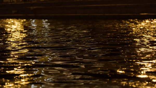 Hermosa vista nocturna de un estanque de la ciudad con ondas. Imágenes de archivo. Primer plano de la superficie del agua en movimiento con el reflejo de las luces de la linterna. —  Fotos de Stock