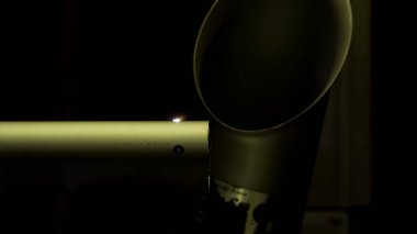 Metal detayları lazerle kesmek için makinenin çalışması. HDR. Siyah zemin üzerinde metal bir tüpte delik açan bir lazer ile endüstriyel arka plan..