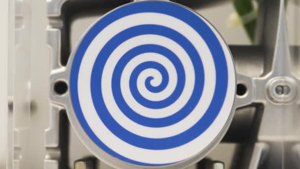 Espiral azul giratorio sobre fondo blanco. HDR. Primer plano del mecanismo automatizado con espiral hipnótica giratoria, concepto de hipnosis y psicoterapia. — Vídeo de stock