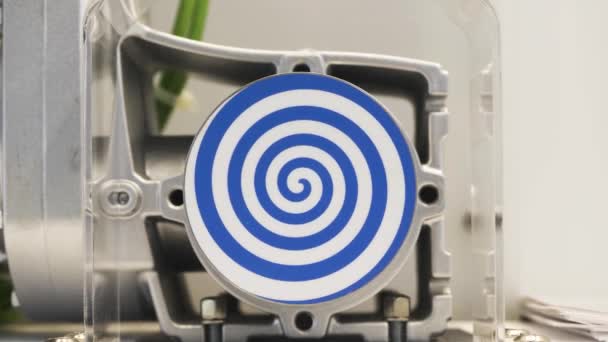 Espiral azul giratorio sobre fondo blanco. HDR. Primer plano del mecanismo automatizado con espiral hipnótica giratoria, concepto de hipnosis y psicoterapia. — Vídeos de Stock
