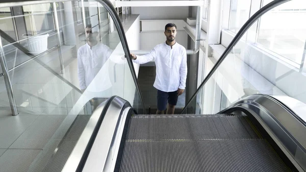 Чоловік у білій сорочці піднімається на ескалатор всередині бізнес-центру. HDR. Молодий чоловік на ескалаторі в універмазі . — стокове фото