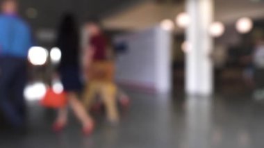 Alışveriş merkezinde yürüyen insanlardan oluşan odaklanmış bir kalabalık. HDR. Yürüyen kadın ve erkeklerle iş merkezinin görüşü bulanık..