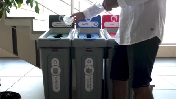 Ein Mann wirft Plastikbehälter in einen öffentlichen Papierkorb. HDR. Mülltrennungskonzept, Recycling-Eimer im Einkaufszentrum. — Stockvideo