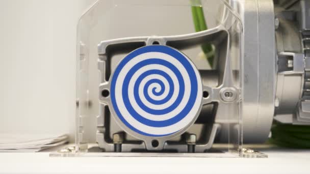 Primer plano del círculo plano blanco giratorio con espiral azul brillante que crea efecto hipnótico. HDR. Robot inusual con círculo hipnótico giratorio automatizado. — Vídeos de Stock