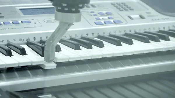 Robotic mechanism plays piano. HDR. Exhibition of robotics with practical performances for demonstration. Primitive robotic hand plays synthesizer. Exhibition of Robotic Equipment — Stock Photo, Image