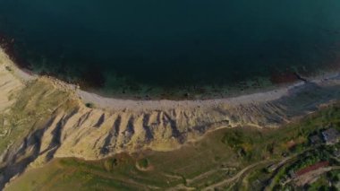 Kıyısı ve mavi suyu olan kayalık kıyı manzarası. Vuruldu. Kayalık sahilin yanındaki taban mavisi. Dağ kıyısında sakin deniz suyu
