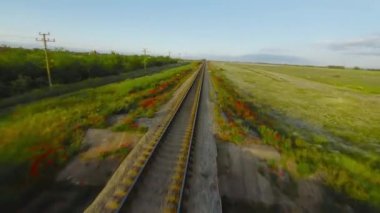 İnsansız hava aracıyla trenle uçmak. Vuruldu. Hızlı tren yolculuğunun en üst manzarası. Kırmızı çiçeklerle dolu boş demiryolu üzerinde güzel bir uçuş.