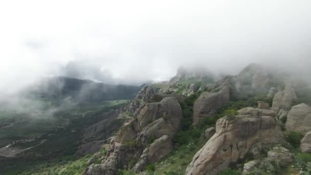 在大雾中的岩石山上飞行。开枪了令人叹为观止的是青山在雾中的岩石斜坡.有岩石山崖的多雾群山的顶部景观 — 图库视频影像