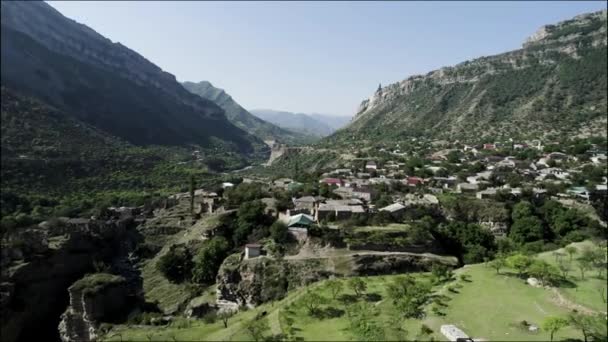 Velha aldeia autêntica entre duas montanhas gigantes. Acção. Vista aérea de uma pequena cidade localizada no vale entre rochas em um dia ensolarado de verão. — Vídeo de Stock