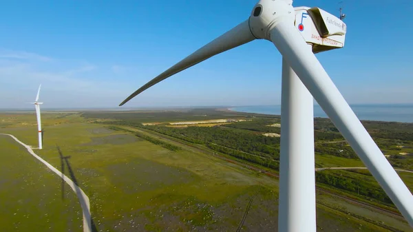Flight at wind turbine. Shot. Exciting flight on drone with wind generators. Top view of wind farm on background of green field and sea