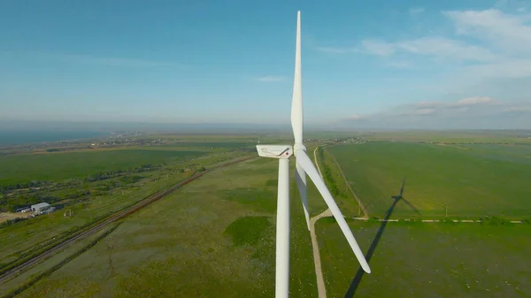 Flight at wind turbine. Shot. Exciting flight on drone with wind generators. Top view of wind farm on background of green field and sea