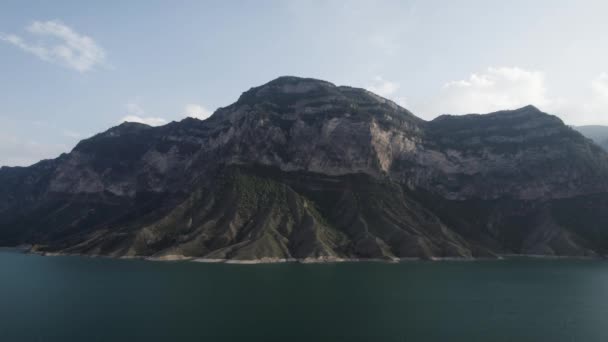Widok z lotu ptaka spokojnej powierzchni wody jeziora w kolorze turkusowym. Akcja. Zapierające dech w piersiach letnie krajobrazy z zboczami górskimi i zbiornikiem wodnym na zachmurzonym tle nieba. — Wideo stockowe