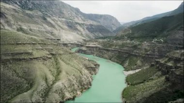 Kayaların arasında akan kıvrımlı yeşil bir nehrin havadan görünüşü. Başla. Resimli bir deresi ve dağ sırası olan yaz doğal manzarası.