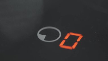 Elektrikli ocağın zamanlayıcı düğmesine yakın çekim. Başla. Parmak, elektrikli sobanın bir tuşuna basıyor. Siyah elektrikli ocağın düğmelerine bas.