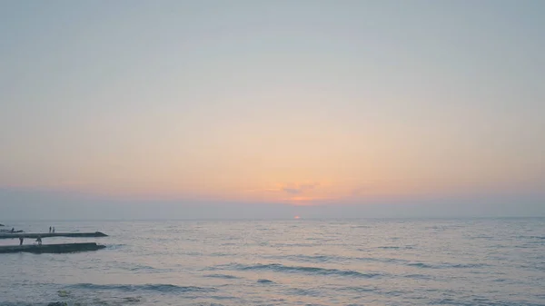 Волны на пляже на закате. Начали. Волны прозрачной воды катятся по скалистому пляжу на фоне заката. Красивый морской пейзаж на закате — стоковое фото