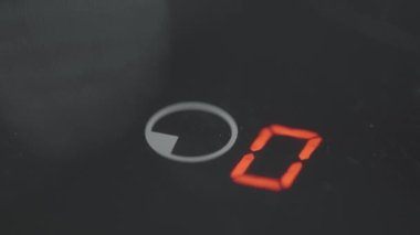 Elektrikli ocağın zamanlayıcı düğmesine yakın çekim. Başla. Parmak, elektrikli sobanın bir tuşuna basıyor. Siyah elektrikli ocağın düğmelerine bas.