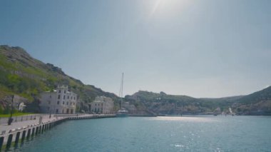 Güneşli bir günde, dağ kıyısındaki eski bir kasaba. Başla. Güney şehrinin eski evleri olan güzel bir sahil. Yeşil dağların ve parlak güneşin arka planında deniz turistik kenti