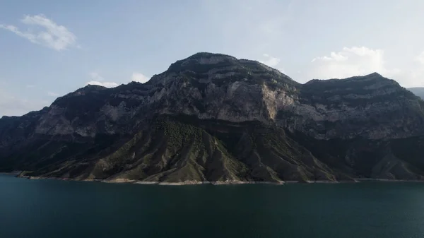 空中俯瞰平静的蓝绿色湖水表面.行动。在多云的天空背景下，有着山体斜坡和水库的令人叹为观止的夏景. — 图库照片