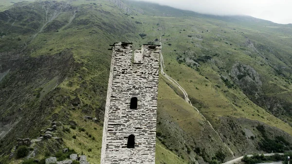 Удивительный вид с воздуха на зеленые горы и древнее каменное здание на вершине холма. Начали. Старая каменная белая заброшенная башня построенная на вершине горы. — стоковое фото
