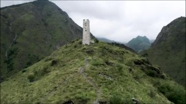 Muhteşem hava manzaralı yeşil dağlar ve tepenin üstündeki antik taş bina. Başla. Dağın zirvesine inşa edilmiş terk edilmiş eski taşlı beyaz kule..