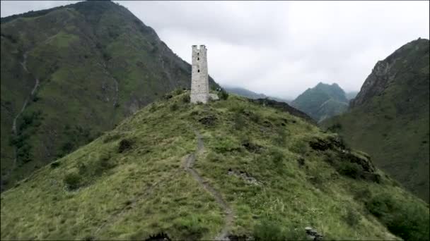 Underbar utsikt över gröna berg och gamla stenbyggnad på toppen av en kulle. Börja. Gammal stenig vit övergiven torn byggt på en bergstopp. — Stockvideo