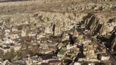 Dağ sırasının yakınındaki küçük bir kasabanın havadan görünüşü. Başla. Kızıl Türkçe bayrak sallanıyor kayaların tepesinde, güneşli bir köy kuru alanda.