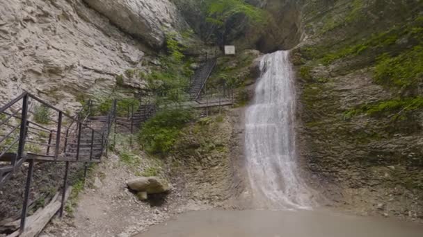Маленький красивый водопад в горах. Начали. Нежный водопад, стекающий со скалы среди зеленых гор. Водопад падает с небольшой скалы в зеленых горах — стоковое видео