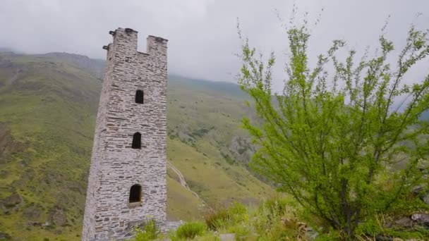 산에 있는 고대 건물들의 돌 탑. 행동. 녹색 산 뒤에 있는 오래 된 돌탑. 산악 지대에 보존되어 있는 고대 건축물 의탑 — 비디오