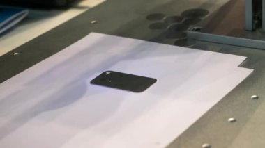 Fiber lazer oyma makinesi sergi ve fuarda metal akıllı telefon panelini işaretliyor. HDR. Tasarım, kişiselleştirme, otomatik teknoloji ekipmanları konsepti.