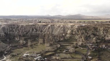 Türkiye 'nin Goreme kenti yakınlarındaki Cappadocia' daki dağların ve kayaların insansız hava aracı görüntüsü. Başla. Bulutlu arka planda evleri olan güzel kayalık bir vadi..