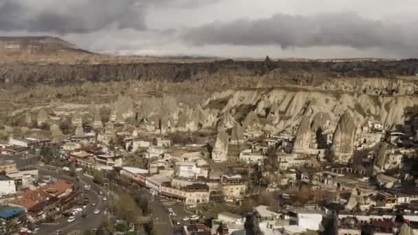 Vista aerea di una piccola città situata vicino alla catena montuosa. Azione. Bandiera turca rossa sventola su una cima di roccia, villaggio soleggiato in zona asciutta. — Video Stock