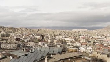 Türkiye 'deki eski Kapadokya Parkı' nın havadan görünüşü. Başla. Bulutlu arka planda kayalarla çevrili taş evler ve binalar..