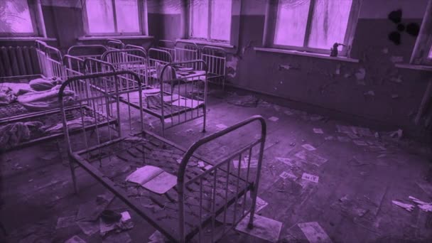 Dormitorio de niños abandonados en el jardín de infantes, detalles de una ciudad fantasma en colores púrpura, Pripyat, Ucrania. Moción. Espantosas camas de metal antiguas para niños dentro del edificio en ruinas. — Vídeos de Stock