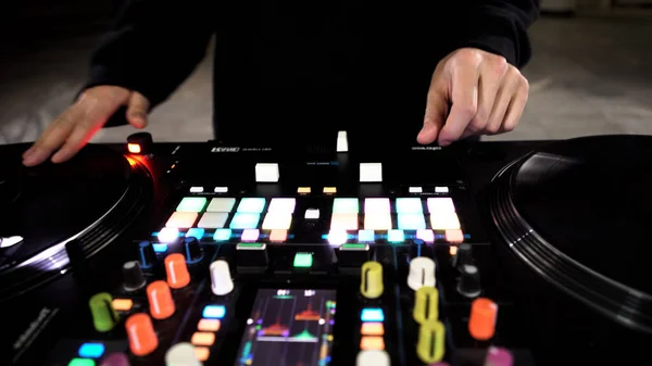 Primo piano di DJ utilizzando un mixer audio moderno per la riproduzione di musica elettronica presso il nightclub. Art. Bottoni colorati e vinile, attrezzatura di un deejay. — Foto Stock