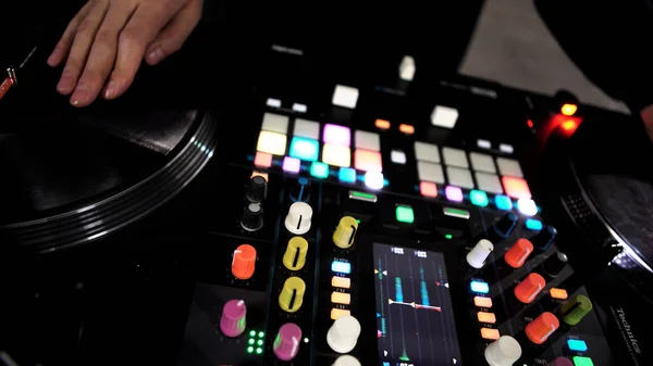 Primer plano de DJ usando un mezclador de sonido moderno para reproducir música electro en la discoteca. Art. Botones de colores y vinilo, equipo de un DJ. — Foto de Stock