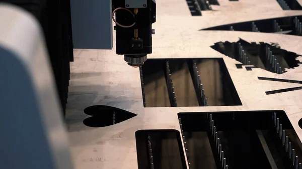 Presentatie van industriële apparatuur op de technologische tentoonstelling. HDR. Lasermetaal snijmachine creëren van een hartvormig gat op een vlakke plaat van metaal staal materiaal. — Stockfoto