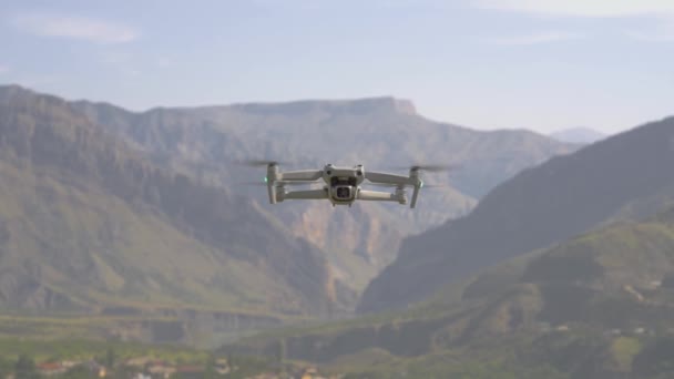 Quadcopter flyr på fjellgrunn. Handling. Utsikt over kvadrokopter som flyr i luften på bakgrunn av fjell. Quadcopter tar bilder av fjellandskap på solfylte dager – stockvideo