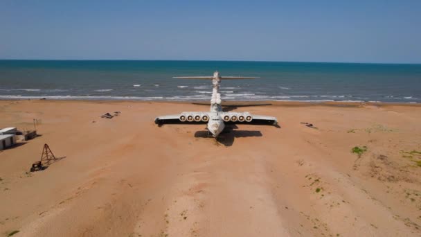 Velho avião na praia. Acção. O avião militar aterrou na costa do mar há muitos anos. Avião militar abandonado à beira-mar com história — Vídeo de Stock