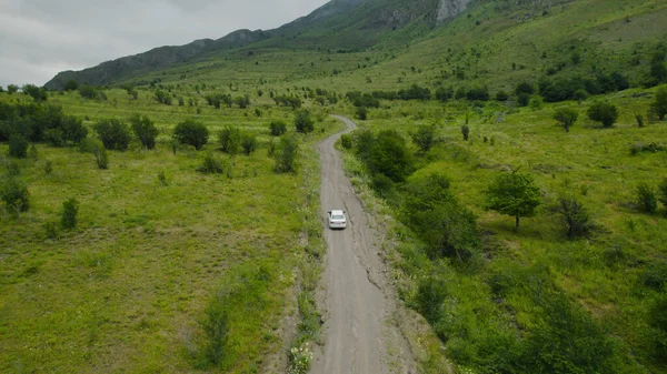 Top view of car driving on road near green mountains. Action. Beautiful car ride through mountain places. Single car is driving on road on background of green mountains — Stock Photo, Image