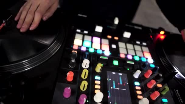 Tutup DJ menggunakan mixer suara modern untuk bermain musik elektro di klub malam. Seni. Kancing berwarna dan vinil, peralatan seorang deejay. — Stok Video