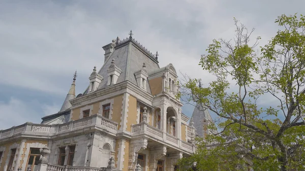 Hermosa fachada de palacio europeo sobre fondo de árboles y cielo. Acción. Palacio amarillo en estilo europeo con jardín. Massandra Palace en la Crimea — Foto de Stock