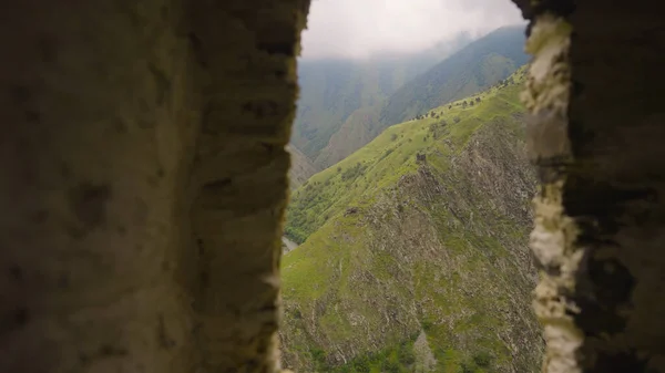 Krásný výhled na hory z okna zříceniny. Akce. Kamenný oblouk z trosek s výhledem na zelené hory. Zelené hory z okna trosek — Stock fotografie