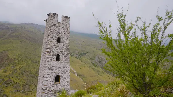 Каменные башни древних зданий в горах. Начали. Старая каменная башня на фоне зеленых гор. Сохранившаяся башня древнего строения в горах — стоковое фото