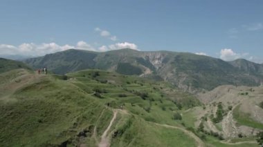 Mavi bulutlu arka planda yeşil tepe manzaralı güzel bir hava manzarası. Başla. Yeşil otlar ve büyüyen ağaçlarla kaplı dağların üzerinde uçuyorlar..