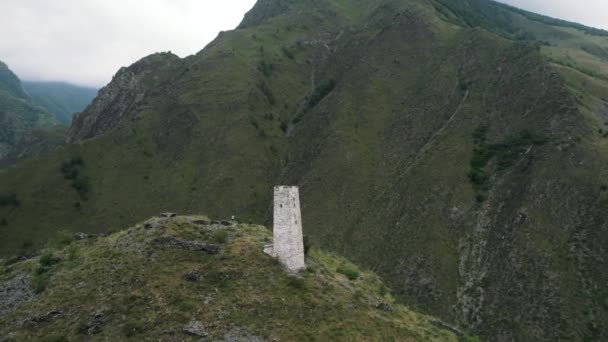 Légi felvétel az ősi temetkezési szerkezetről Tsoy Pede, Csecsen Köztársaság, Oroszország. Felvétel. Fehér torony egy zöld hegy tetején, hegyekkel körülvéve.. — Stock videók