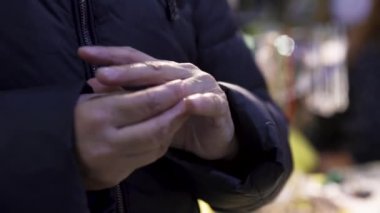 Parmağına yüzük takmaya çalışan yaşlı bir kadını yakından çek. - Sanat. Yüzük takmaya çalışan, kalın ceketli yaşlı bir kadın..