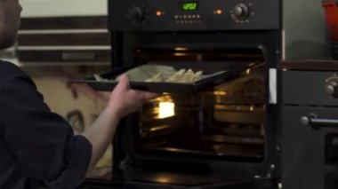 Hamur köftelerini fırının içine koymaya yaklaş. - Sanat. Tepside hamur tatlısı pişirmek, evde yemek pişirmek..