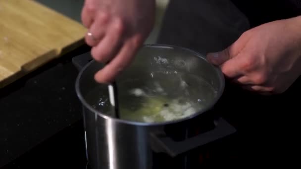 Close-up de preparar sopa, caldo com batata e grãos de pimenta preta. Arte. Chef mãos mexendo sopa com uma espátula de cozinha. — Vídeo de Stock