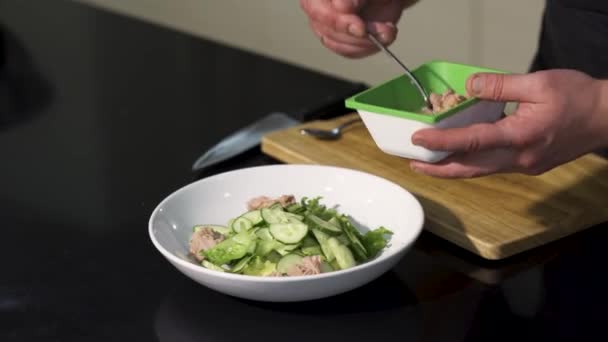 Ensalada orgánica fresca con atún en tazón blanco. Art. Primer plano de las manos del chef añadiendo pescado en la ensalada verde en la cocina, concepto de cocina de alimentos. — Vídeos de Stock